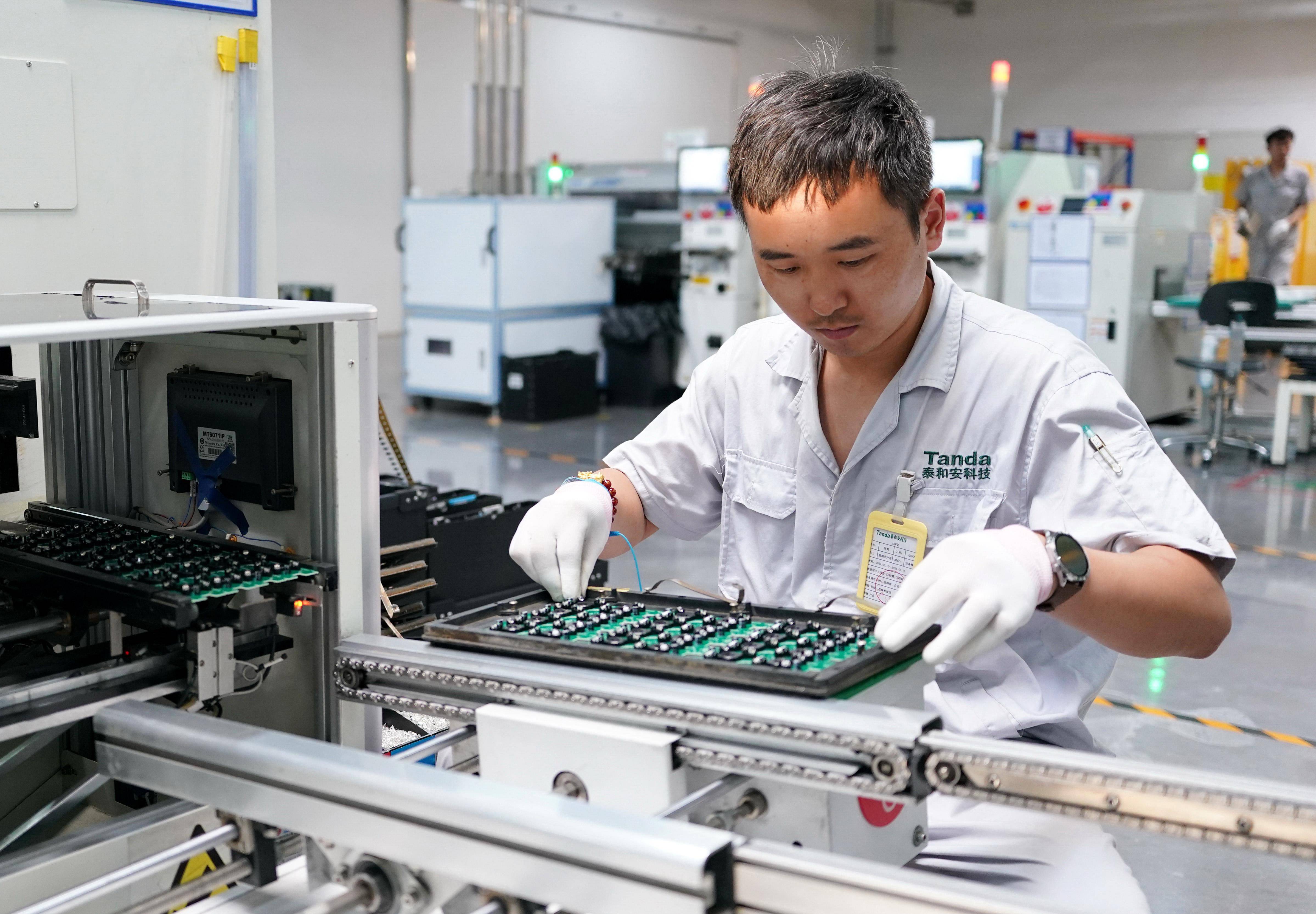 Workers assembling small desktop robots at a production bench